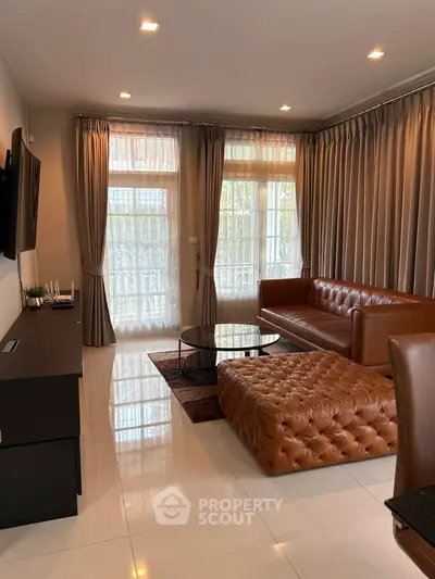 Elegant living room with leather sofa, large windows, and modern decor