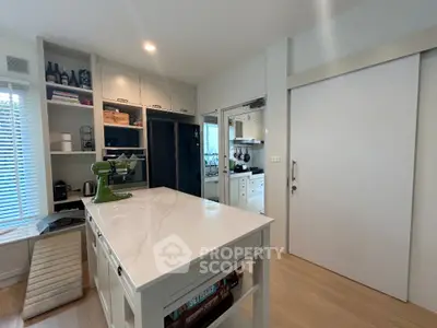 Modern kitchen with white marble island, sleek cabinetry, and high-end appliances, perfect for culinary enthusiasts.