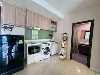 Modern kitchen with sleek appliances and view into stylish bathroom