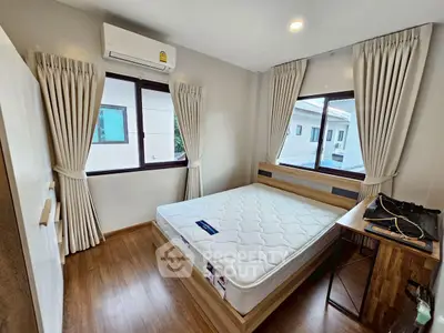 Cozy bedroom with wooden flooring, large windows, and modern furnishings.