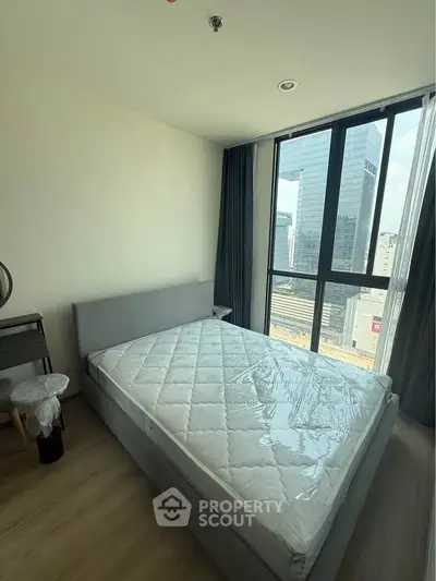 Modern bedroom with large window and city view in high-rise apartment