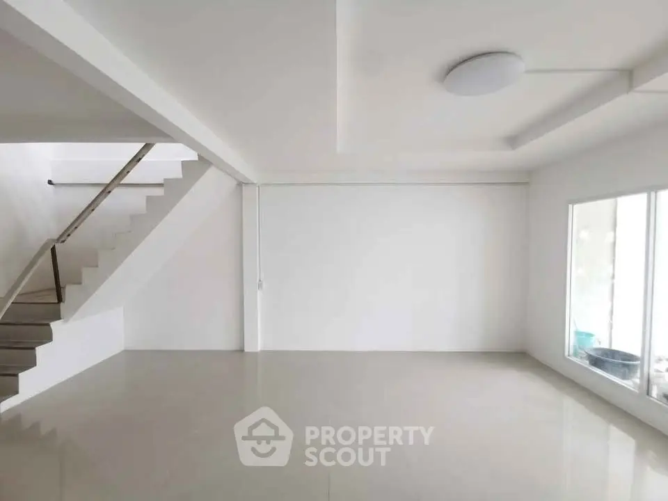 Spacious modern living room with minimalist design and large window for natural light.