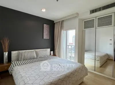 Modern bedroom with mirrored closet and city view from window.