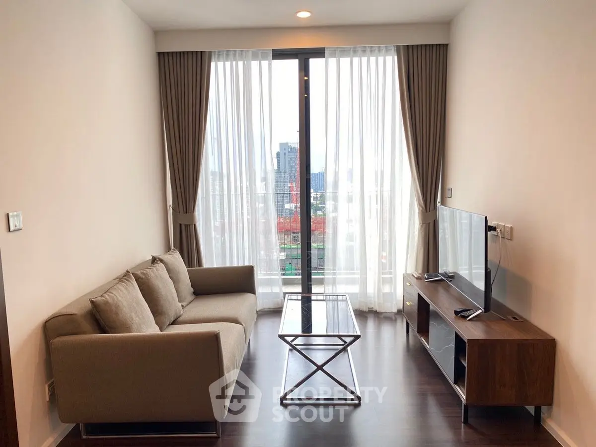 Modern living room with city view, stylish sofa, and sleek TV setup.