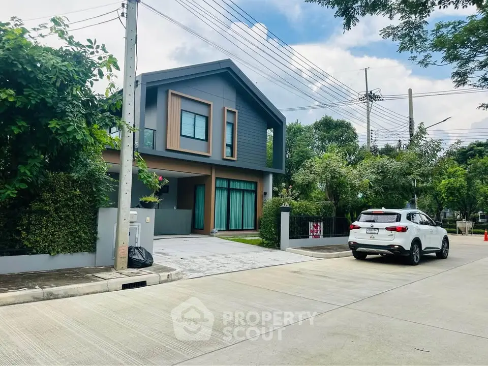 Modern two-story house with driveway and lush greenery in suburban neighborhood.