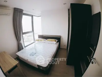 Cozy bedroom with large window and modern furnishings in a bright apartment.