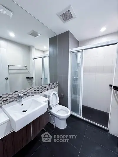 Modern bathroom with sleek design, featuring a glass shower enclosure and stylish sink.