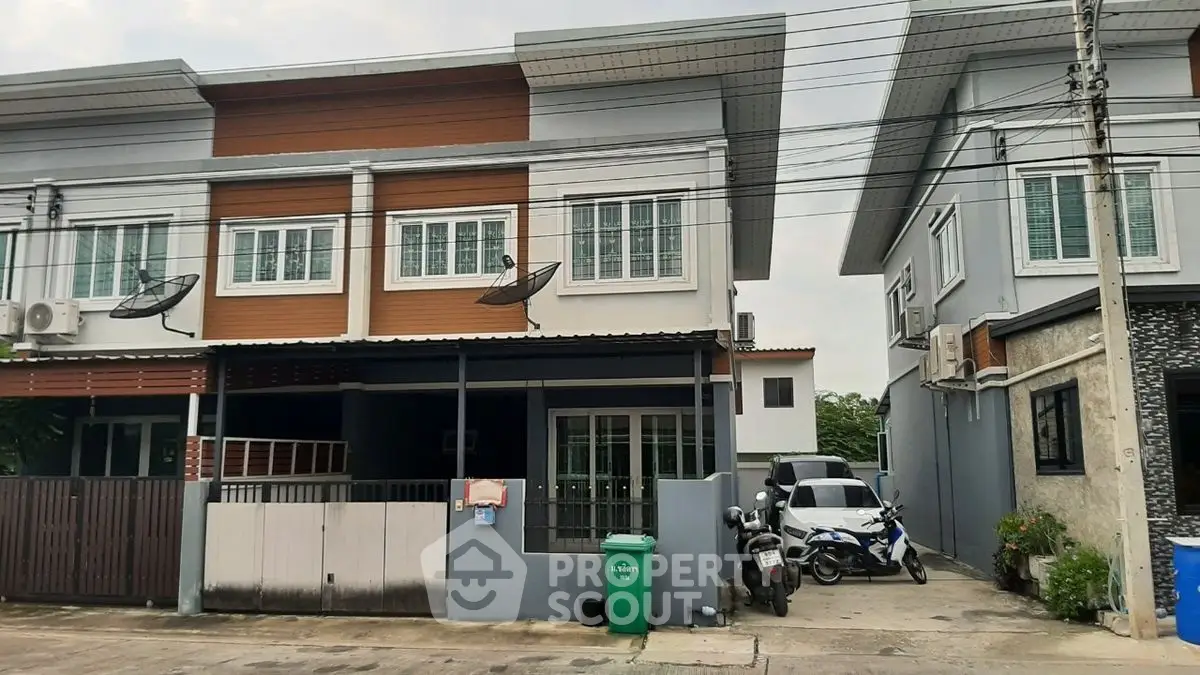 Modern townhouse exterior with parking space and satellite dishes in a suburban neighborhood.