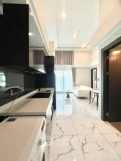 Modern open-plan living room with sleek kitchen and marble flooring, featuring high ceilings and natural light.