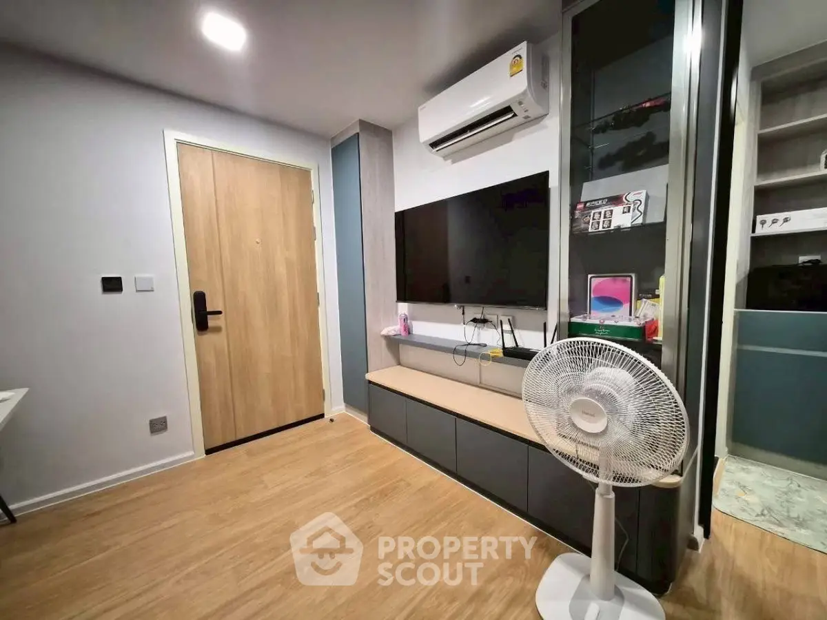 Modern living room with sleek design, featuring a wall-mounted TV, air conditioning, and stylish wooden flooring.
