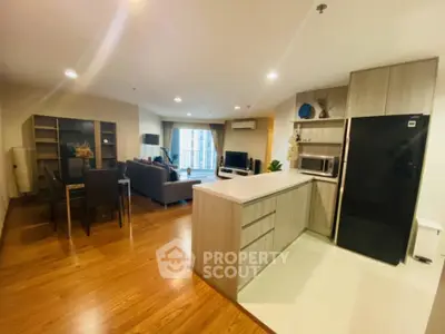 Spacious open-plan living room and kitchen with modern furnishings and wooden flooring.