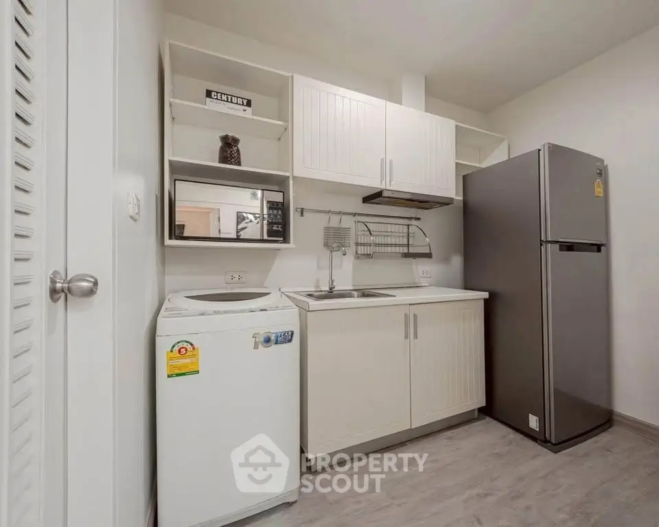 Modern compact kitchen with washing machine and fridge in a sleek apartment