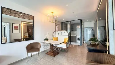 Elegant living room with modern decor and built-in laundry area, featuring stylish seating and chandelier.