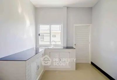 Bright minimalist kitchen with sleek countertops and ample natural light.