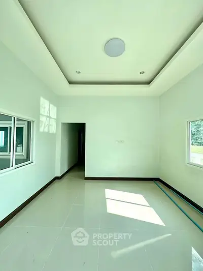 Spacious empty room with modern ceiling design and large windows