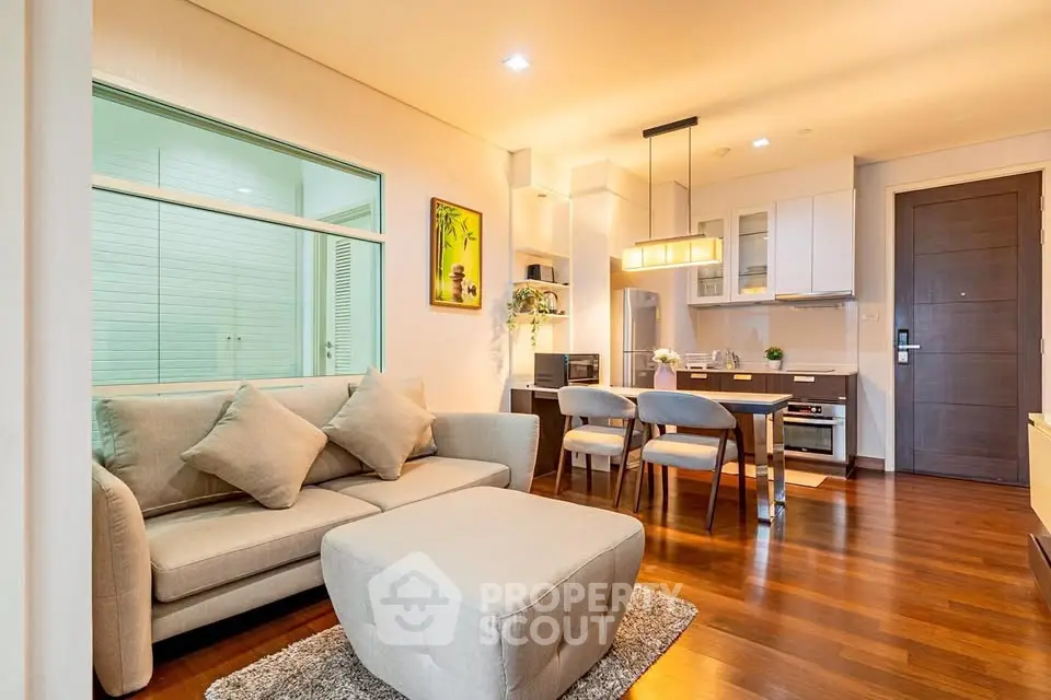 Modern open-plan living room with cozy seating and stylish kitchen in a bright apartment.