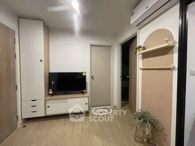 Modern living room with sleek TV unit and air conditioning, featuring stylish decor and wooden flooring.
