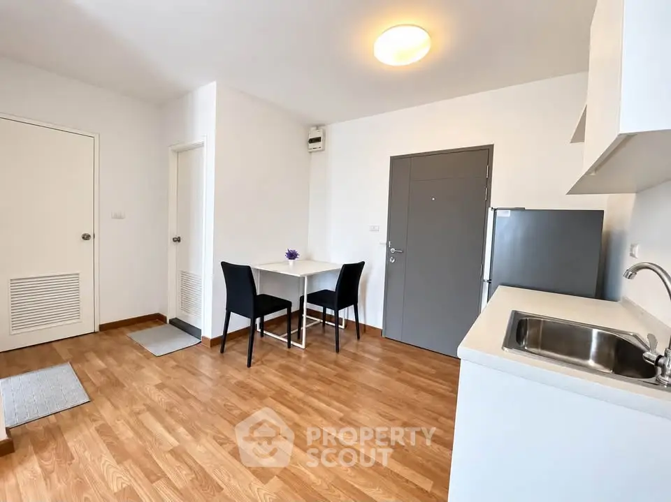Modern kitchen with sleek design, wooden flooring, and compact dining area in a cozy apartment.