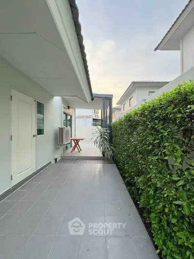 Charming exterior walkway with lush greenery and modern architecture in a serene neighborhood.