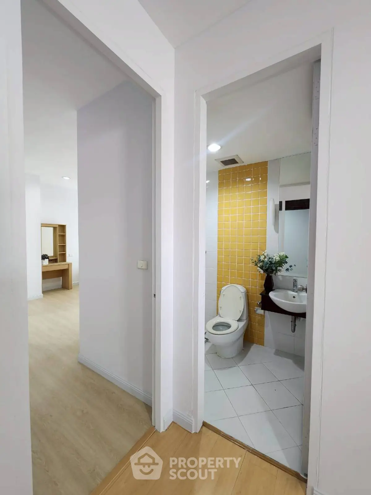 Modern apartment hallway with bathroom and living area view, featuring sleek design and bright interiors.