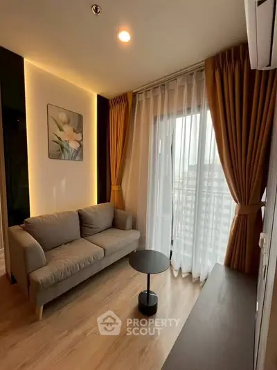 Cozy living room with modern decor and large window offering natural light.