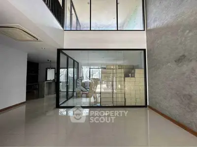 Modern open-concept living space with glass-enclosed room and sleek design.