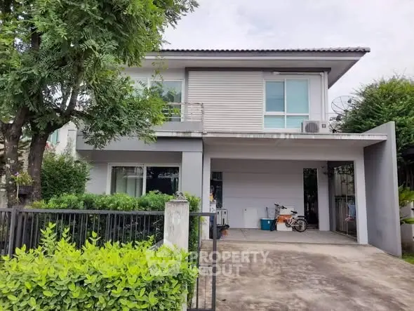 Modern two-story house with driveway and lush greenery in suburban setting.