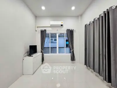 Modern living room with sleek tile flooring, air conditioning, and large window for natural light.