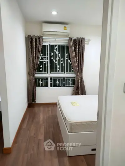 Cozy bedroom with wooden flooring and air conditioning in modern apartment