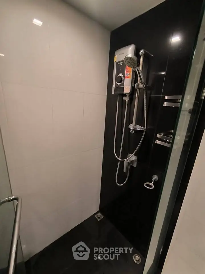 Modern bathroom with sleek black and white tiles and a high-end shower system.