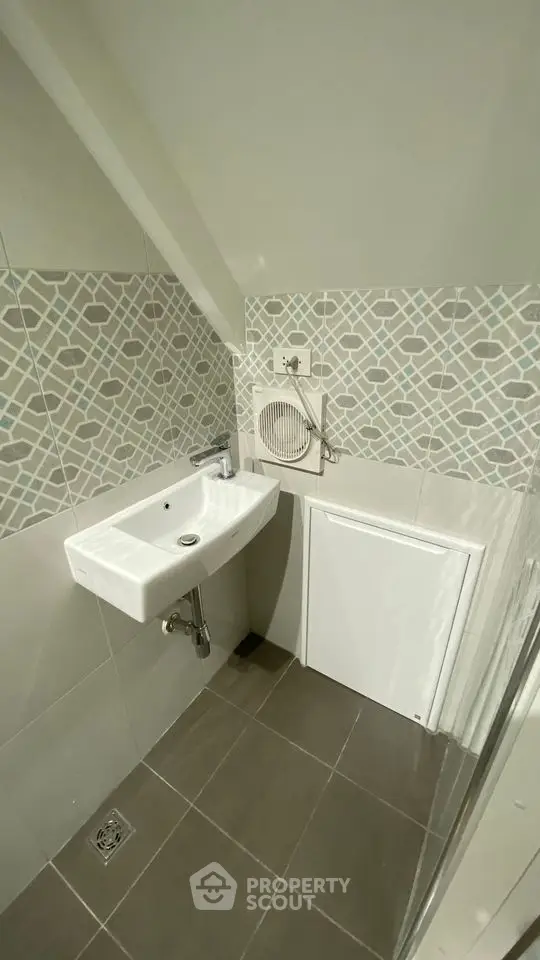 Compact bathroom with modern sink and geometric tile design