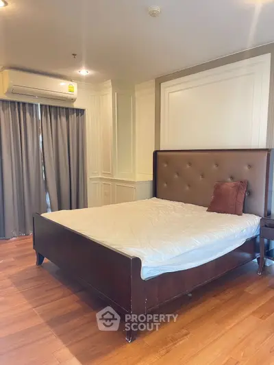 Spacious bedroom with elegant wooden flooring and modern air conditioning unit.