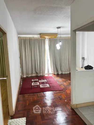 Spacious living room with wooden flooring and modern lighting, ideal for cozy gatherings.