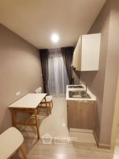 Modern compact kitchen with dining area and sleek cabinetry in cozy apartment.