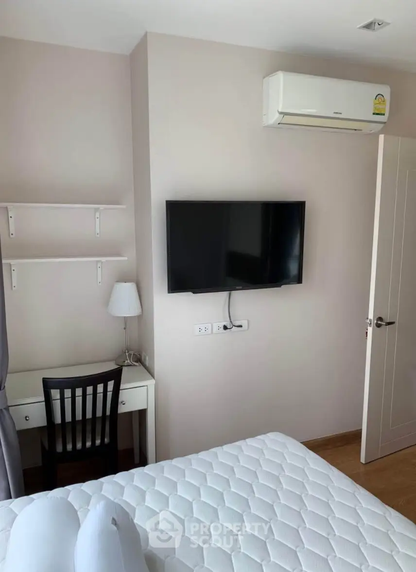 Cozy bedroom with wall-mounted TV and air conditioning, perfect for relaxation.