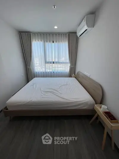 Modern bedroom with large window and air conditioning in a stylish apartment.