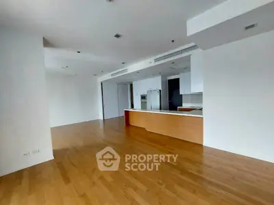 Spacious open-plan kitchen with sleek wooden flooring and modern appliances.