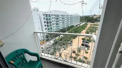 Charming balcony with scenic view of modern apartment complex and lush greenery.