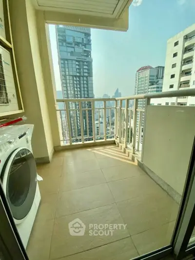 Spacious balcony with city view and washing machine in modern high-rise apartment.