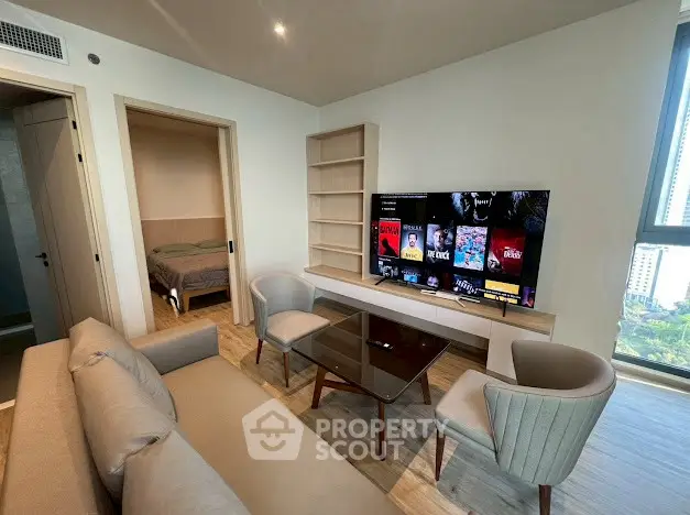 Modern living room with stylish furniture and a wall-mounted TV, adjacent to a cozy bedroom.