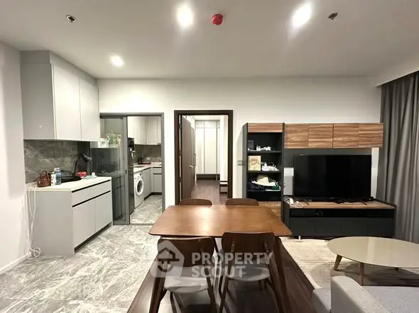 Modern open-plan living room with dining area and kitchen, featuring sleek furniture and contemporary design.