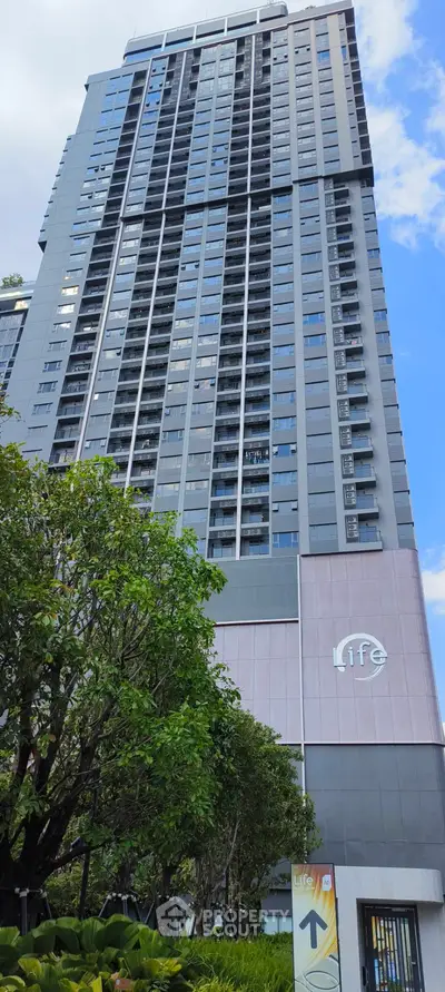 Modern high-rise building with lush greenery and clear blue sky