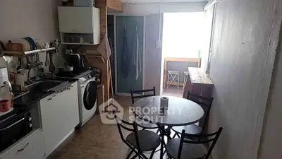 Cozy kitchen with gas stove, oven, and washing machine, complemented by a dining area with a round table and chairs, offering a practical and inviting space.