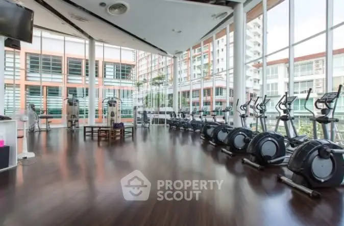 Spacious gym with modern equipment and large windows in a luxury residential building.