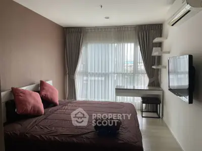 Modern bedroom with large window, stylish decor, and wall-mounted TV in a cozy apartment.