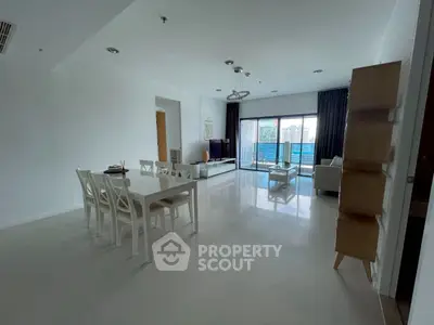 Spacious modern living room with dining area and city view balcony in luxury apartment.