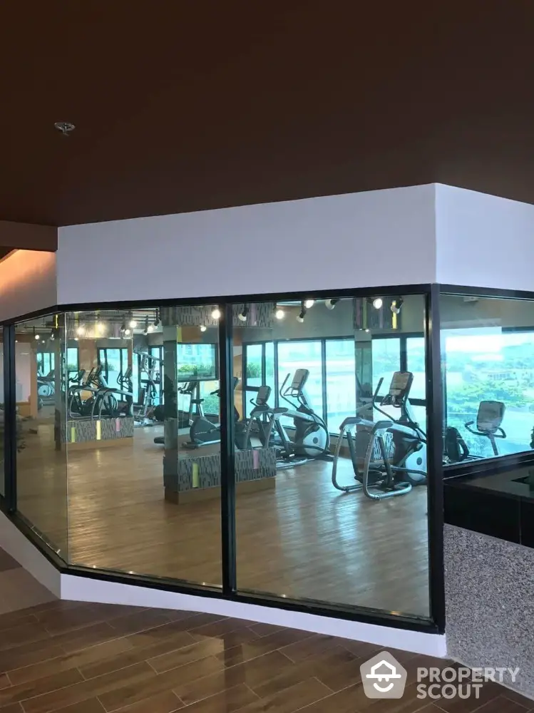 Modern gym with large windows and exercise equipment in a real estate property.