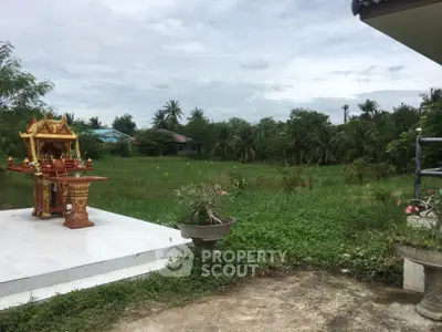 Expansive green land with tropical trees and decorative shrine, perfect for serene living or development.