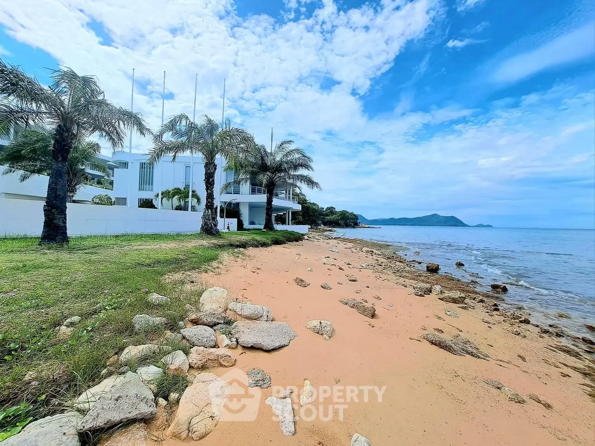 Stunning beachfront property with modern architecture and lush palm trees, offering serene ocean views.