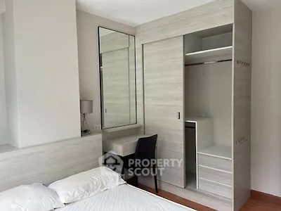 Elegant bedroom with built-in wardrobe and large mirror, showcasing a minimalist design with neutral tones and ample natural light.